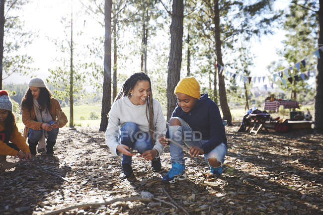 Mother and son gathering firewood kindling at campsite in sunny woods — Stock Photo