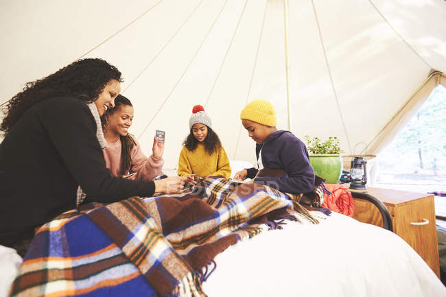 Lesbian couple and kids playing cards on bed in camping yurt — Stock Photo