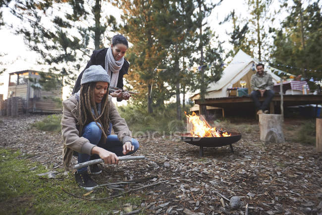 Amici che raccolgono legna da ardere accesa nel campeggio nel bosco — Foto stock