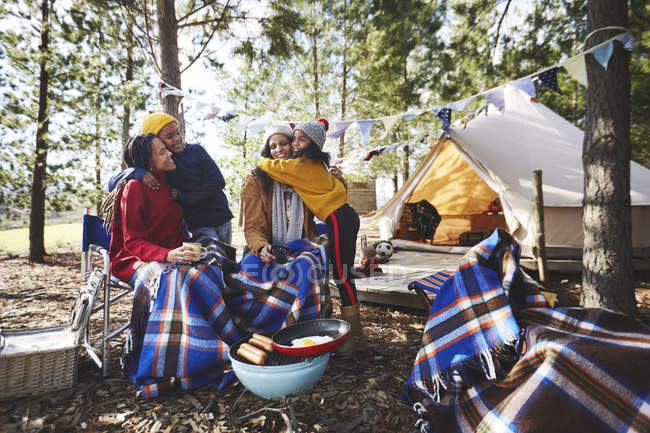Feliz, casal lésbico afetuoso e crianças relaxando no acampamento na floresta — Fotografia de Stock