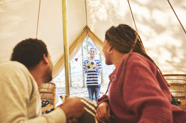 Casal assistindo filho com bola de futebol no acampamento yurt porta — Fotografia de Stock