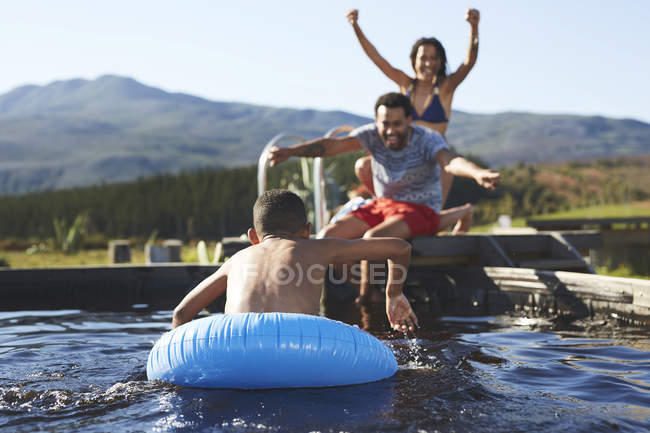 Giocoso nuoto familiare nella soleggiata piscina estiva — Foto stock