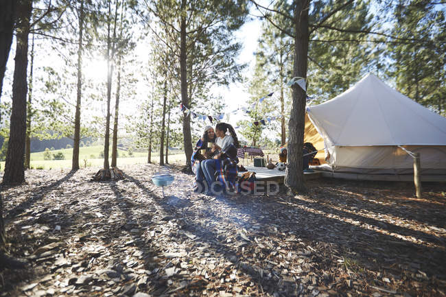Glückliches, anhängliches lesbisches Paar entspannt, trinkt Kaffee auf sonnigem Campingplatz im Wald — Stockfoto