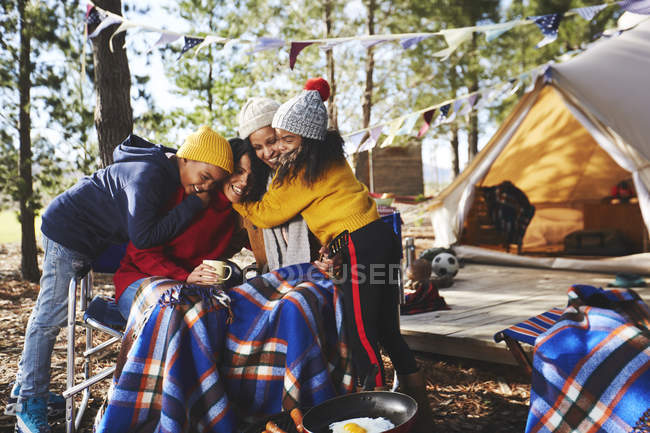 Happy, affectionate lesbian couple and kids hugging at campsite — Stock Photo