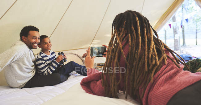 Mulher com câmera telefone fotografar marido e filho no acampamento yurt — Fotografia de Stock