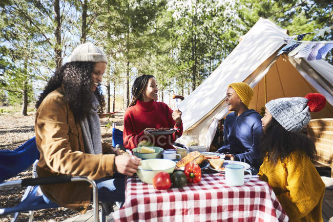 Casal de lésbicas e crianças comendo no acampamento ensolarado — Fotografia de Stock