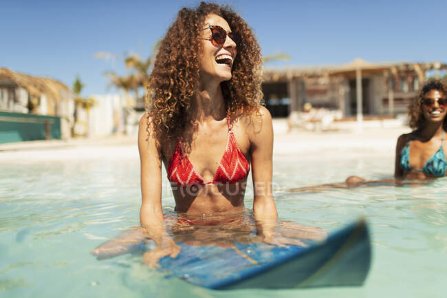 Joyeux jeune femme sur planche de surf dans l'océan ensoleillé — Photo de stock
