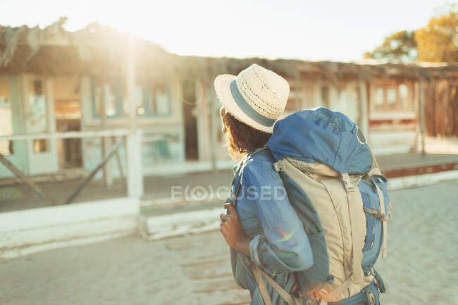 Junge Backpackerin nähert sich sonniger Strandhütte — Stockfoto