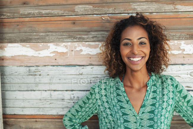 Retrato feliz, joven confiada contra la pared de madera tablón - foto de stock