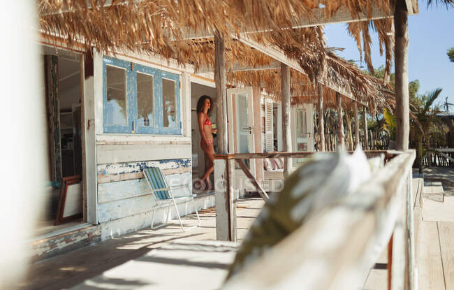 Женщина в бикини, стоящая в дверях солнечной пляжной хижины — стоковое фото