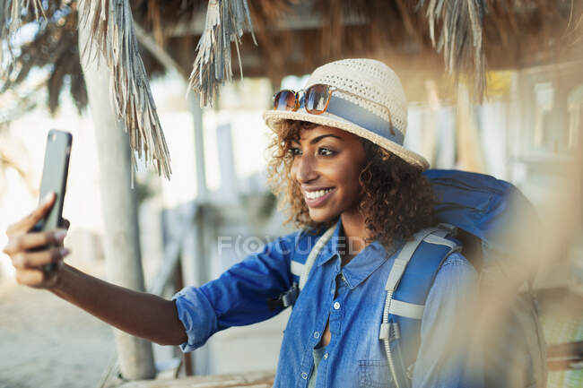 Happy young female backpacker taking selfie with camera phone — Stock Photo