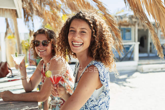 Retrato mujeres felices bebiendo cócteles en el soleado bar de la playa - foto de stock