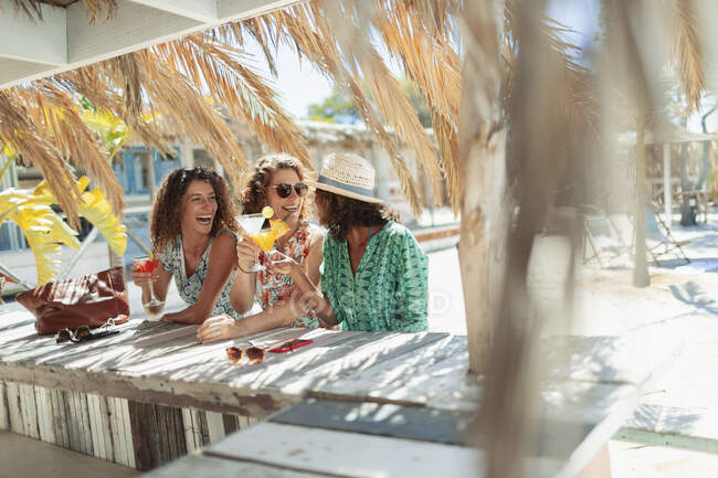 Happy women drinking cocktails at sunny beach bar — Stock Photo