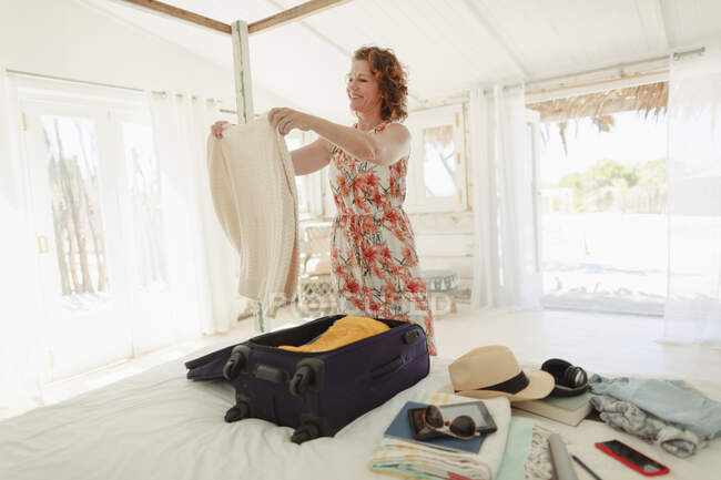 Woman unpacking suitcase in beach hut bedroom — Stock Photo