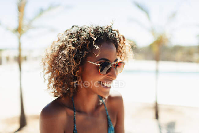 Glückliche junge Frau mit Sonnenbrille am sonnigen Strand — Stockfoto