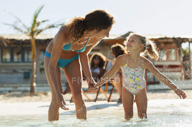 Счастливые мать и дочь играют в солнечном океане — стоковое фото