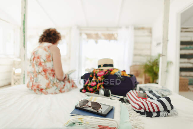 Mujer desempacar maleta en la playa casa dormitorio - foto de stock