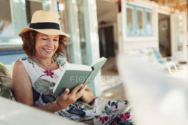 Счастливая женщина читает книгу во внутреннем дворике хижины — стоковое фото