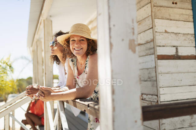 Portrait happy woman on sunny beach hut patio — Stock Photo
