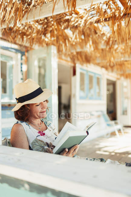 Frau liest Buch auf der Terrasse der Strandhütte — Stockfoto