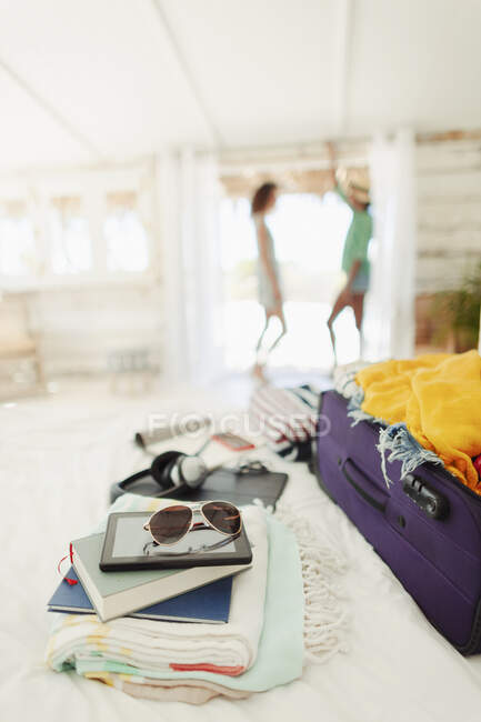Mala, livros, toalhas de praia e óculos de sol na cama da cabana de praia — Fotografia de Stock