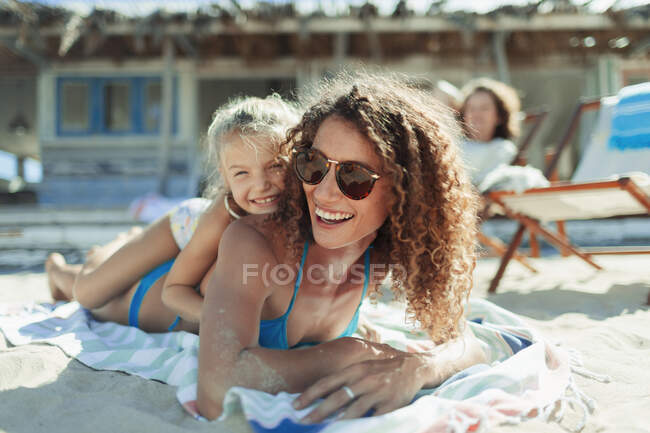 Retrato mãe feliz e filha relaxando na praia ensolarada — Fotografia de Stock