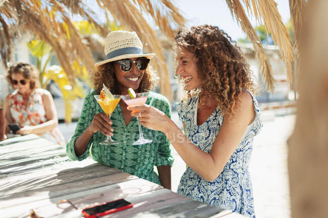 Felice giovane donna amici bere cocktail sulla spiaggia soleggiata bar — Foto stock
