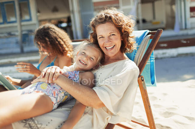 Portrait happy grandmother and granddaughter relaxing on sunny beach — Stock Photo