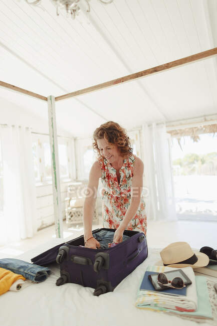 Frau packt Koffer im Schlafzimmer einer Strandhütte aus — Stockfoto