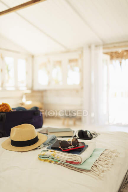 Mala, chapéu de sol, óculos de sol e livro na cama da cabana da praia — Fotografia de Stock