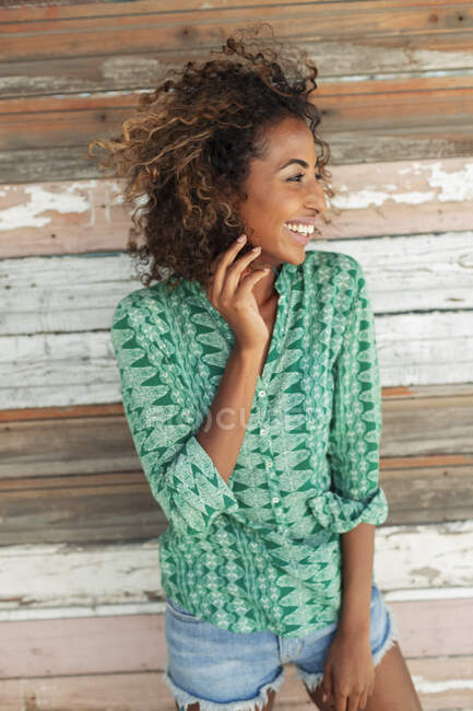 Portrait happy young woman against wood plank wall — Stock Photo