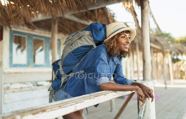 Happy young female backpacker on beach hut patio — Stock Photo