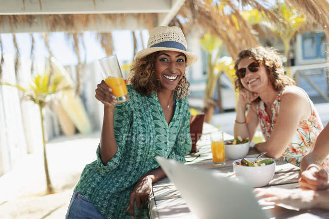 Retrato mujer feliz bebiendo cóctel en soleado bar de playa - foto de stock