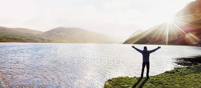 Вид сзади взволнованного человека на солнечном озере — стоковое фото