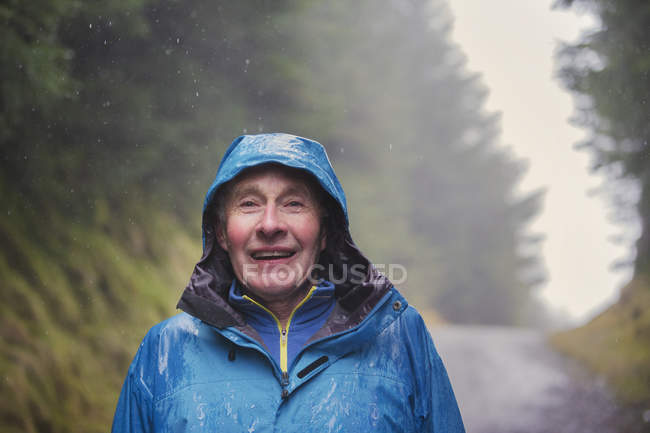 Портрет пожилого человека, путешествующего под дождем — стоковое фото