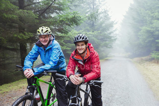 Портрет отца и сына на горном велосипеде под дождем — стоковое фото