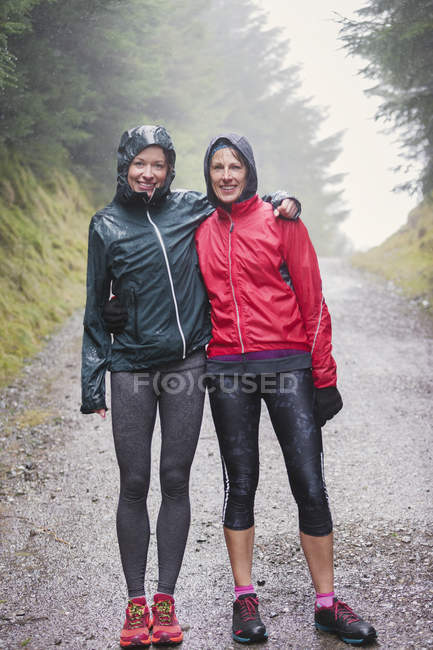 Retrato de madre e hija haciendo senderismo bajo la lluvia - foto de stock