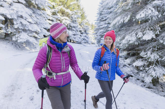 Madre e hija de senderismo en bosques nevados - foto de stock