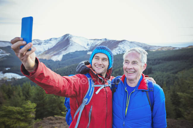 Pai e filho tomando selfie com montanhas no fundo — Fotografia de Stock