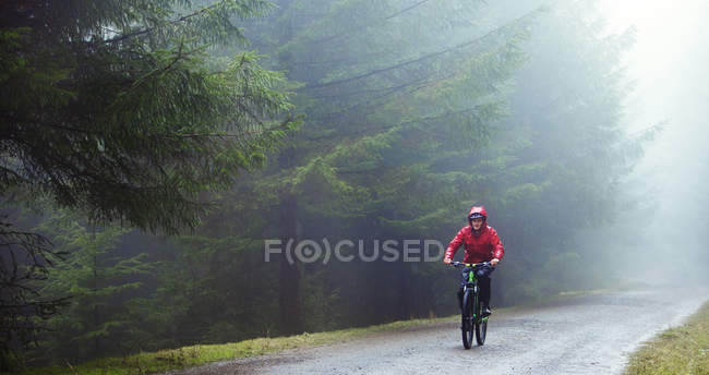 Человек катается на горном велосипеде под дождем — стоковое фото