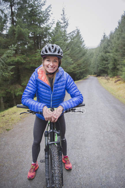 Portrait of smiling woman mountain biking — Stock Photo