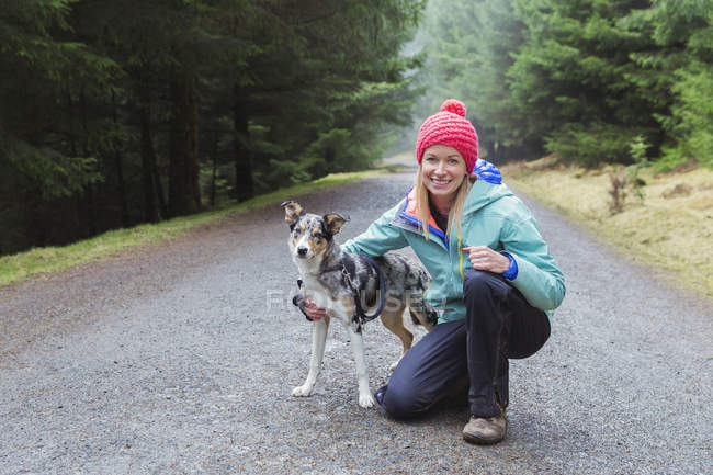 Portrait of woman hiking with dog in woods — Stock Photo