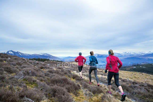 Friends jogging along mountain trail — Stock Photo