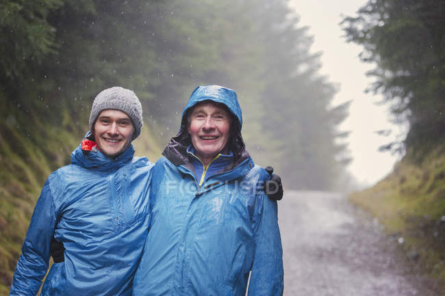 Portrait of father and son hiking in rain — Stock Photo