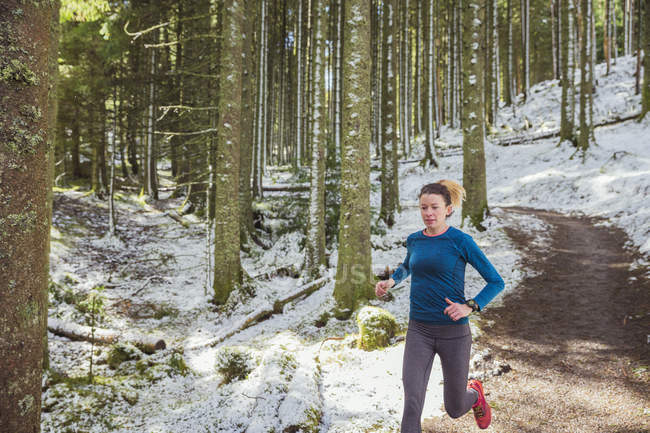 Жінка біжить у засніженому лісі — стокове фото