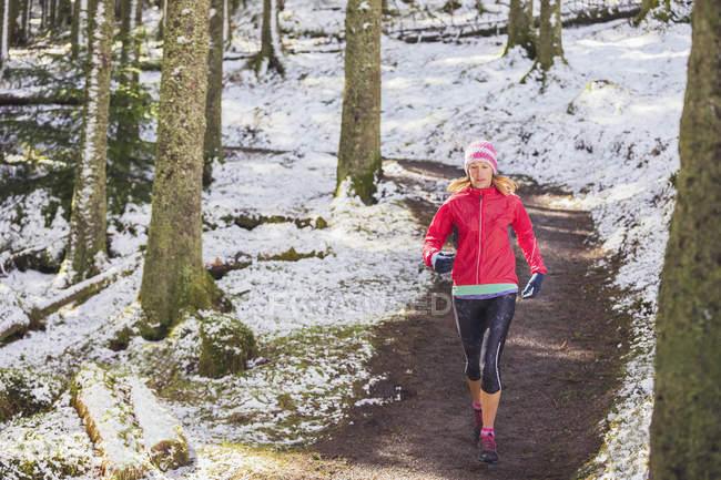 Frau joggt im verschneiten Wald — Stockfoto