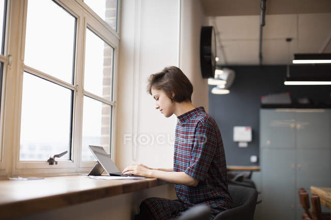 Предпринимательница, работающая за цифровым планшетом в окне офиса — стоковое фото