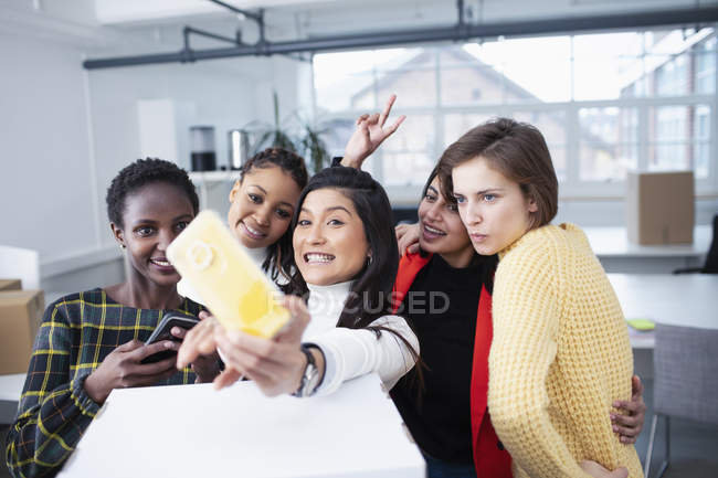 Happy businesswomen moving into new office, taking selfie — Stock Photo