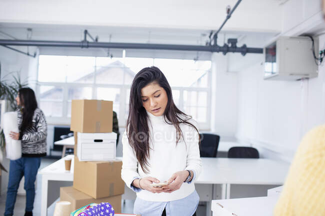 Businesswoman using smart phone in new office — Stock Photo