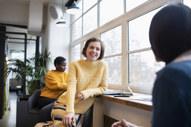 Mujeres de negocios sonrientes hablando en la oficina - foto de stock